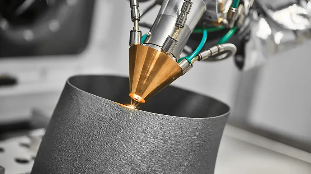 Close-up of industrial 3D printer head using a laser to fuse metal powder, building a cylindrical part layer by layer. Sparks fly as the material is deposited.